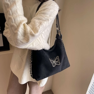 Minimalist black tote bag with butterfly embroidery and metal chain strap on model