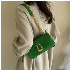 Close-up of a green fashion shoulder bag with a gold metal buckle and chain strap