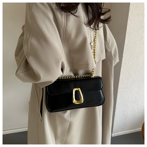Chic black leather crossbody bag featuring a U-shaped gold clasp and chain strap on a model