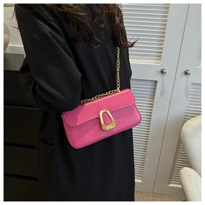 Detail of trendy pink crossbody bag with a thick gold buckle on a black coat