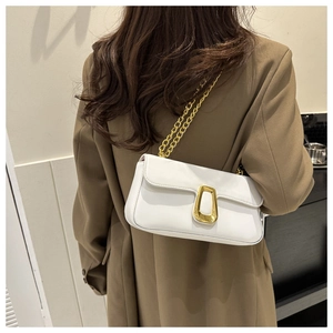 Close-up of white leather shoulder bag with large gold buckle and chunky chain strap