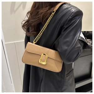 Detail of tan square crossbody bag with gold horseshoe buckle on black leather blazer