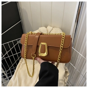 Detail of caramel brown leather handbag featuring a gold buckle and chain strap