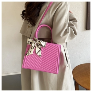 Detail of fuchsia chevron quilted handbag with decorative silk scarf on the handle