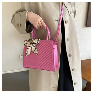 Close-up of pink chevron quilted tote bag with decorative silk scarf and shoulder strap