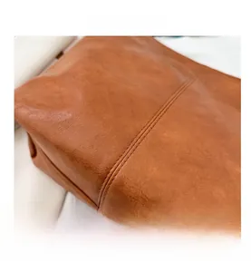 Gros plan du sac seau en cuir marron caramel montrant les coutures et la texture fine
