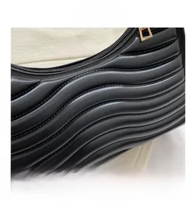 Close-up of black leather bag featuring wavy quilted texture and gold zipper hardware