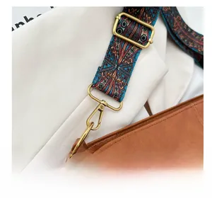Détail de la large bandoulière à motifs et du fermoir doré sur un sac seau marron