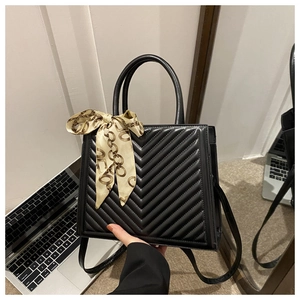 Detail of black quilted shoulder bag with decorative floral silk scarf on handle