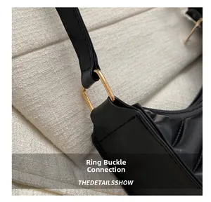 Close-up of golden square metal buckle connecting the black leather shoulder strap