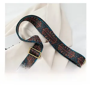 Détail de la bandoulière tissée géométrique avec boucles en laiton sur un sac seau marron