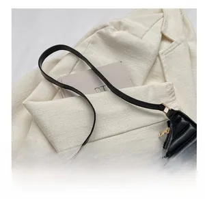 Detail of black quilted leather shoulder bag with gold zipper on tweed blazer outfit