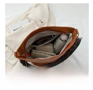 Vue de dessus de l'intérieur du sac seau en cuir marron avec sangle ethnique et accessoires