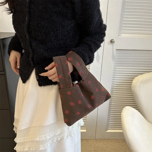 Sac à main en velours côtelé marron à motif fraise porté par un mannequin en style décontracté