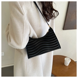 Detailed view of black pleated dumpling bag with wavy leather texture and gold zipper