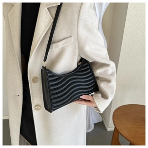 Detail of black quilted shoulder bag featuring premium wave pattern and gold metal buckle