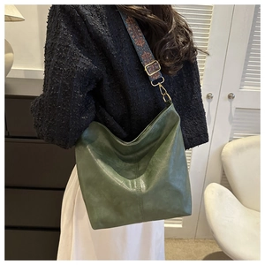 Détail du sac hobo vert foncé avec bandoulière ethnique tissée et boucles dorées mates