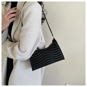 Detail of black wave texture shoulder bag with gold zipper and stylish pleated design