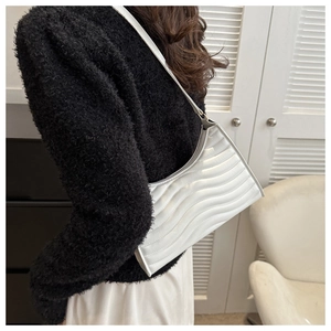 Detail of white quilted underarm bag with wave stitching and slim shoulder strap