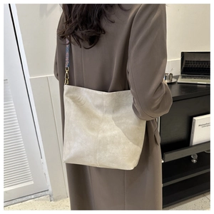 Détails de la bandoulière tissée et des ferrures dorées sur le grand sac seau crème