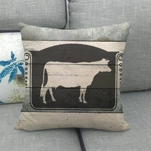 Détail de la taie d'oreiller en lin avec silhouette de vache blanche sur grain de bois