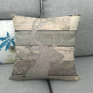 Vue détaillée d'une housse de coussin en lin avec silhouette d'élan et décor bois