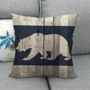 Détail de la housse de coussin en lin avec silhouette d'ours et texture grain de bois