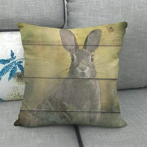 Rustic linen pillow cover with gray rabbit print on a textured wood plank background