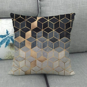 Detail of square linen cushion cover with 3D black and gold geometric patterns on a sofa