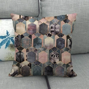 Linen pillowcase with modern geometric hexagon patterns and gold trim on gray sofa