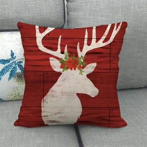 Close-up of red Christmas reindeer pillowcase with rustic linen texture on a sofa