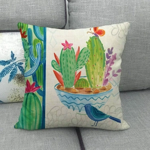 Linen cushion cover with green cactus, blue bird and flower on a grey sofa