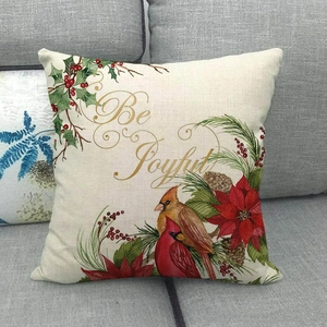 Detail of linen pillowcase with cardinal bird, poinsettia and Be Joyful text on sofa