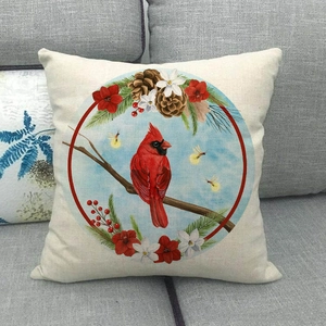 Macro detail of linen pillow cover featuring a red cardinal bird and winter pine cone patterns