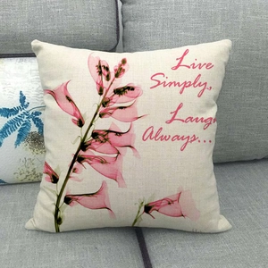Détail d'une housse de coussin en lin avec motif floral sur un canapé gris
