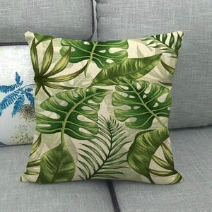 Détail de la housse de coussin en lin avec motifs de feuilles tropicales sur un canapé