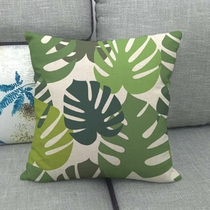 Housse de coussin en lin à feuilles de monstera tropicales sur un canapé gris