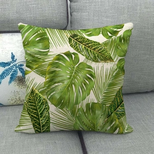 Housse de coussin en lin avec feuilles tropicales et monstera sur un canapé gris