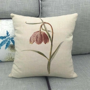 Close-up of a floral linen pillowcase featuring a vintage fritillaria plant on a grey sofa