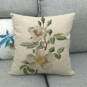 Detail of floral linen pillowcase showing vintage rose print on gray fabric sofa