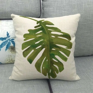 Housse de coussin en lin avec motif de feuille tropicale verte sur un canapé
