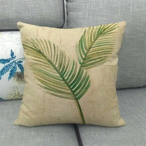 Gros plan d'une taie d'oreiller en lin à motif palmier sur un canapé gris
