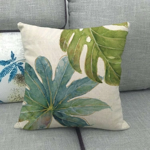 Gros plan d'une housse de coussin en lin avec motif de feuilles tropicales sur un canapé