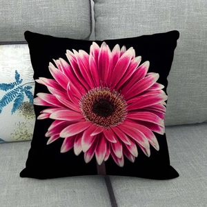 Linen pillowcase with pink gerbera daisy print on black background on grey sofa