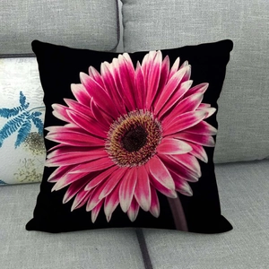 Detail of pink gerbera daisy floral print on black linen pillowcase on a grey sofa