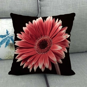Detailed close-up of a black linen pillowcase with a vibrant red gerbera daisy print