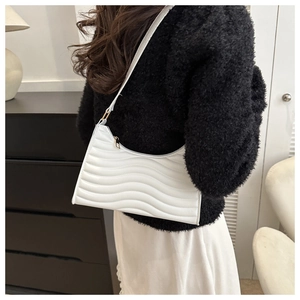 Detail of white underarm bag with horizontal wavy quilted texture and gold zipper