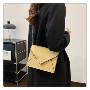 Detailed side view of a beige leather flap bag with silver chain strap and V-clasp