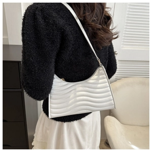 Lifestyle view of a white quilted shoulder bag with unique wave stitching on a model