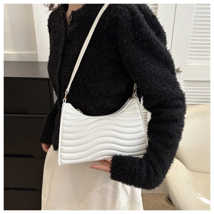 Detail of white crescent underarm bag with elegant wave quilted texture and PU leather